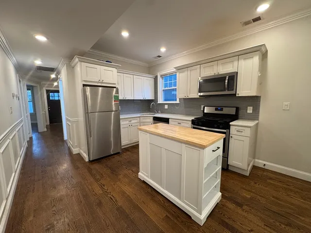 a kitchen with a refrigerator a stove top oven and wooden floor
