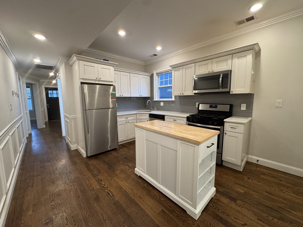 9 Cornwall Street, Unit 1 Boston, MA 02130 - Photo 11 of 22 a kitchen with a refrigerator a stove top oven and wooden floor
