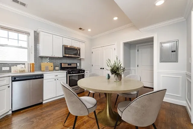 a kitchen with stainless steel appliances granite countertop a stove a microwave a sink a dining table and chairs