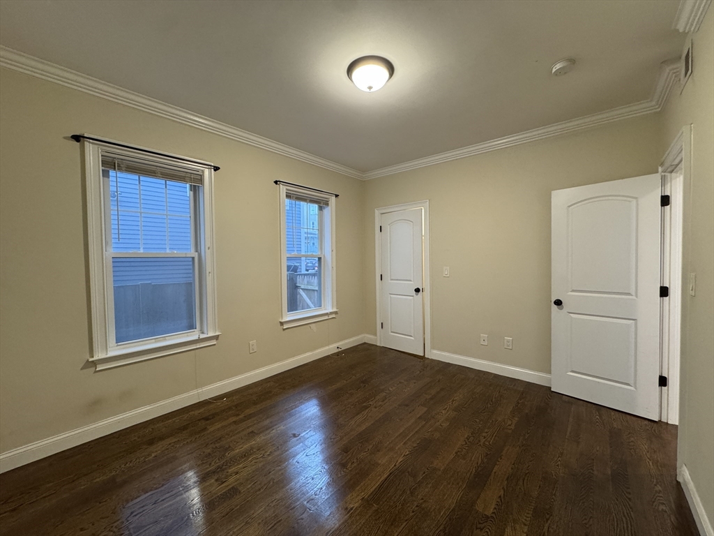 9 Cornwall Street, Unit 1 Boston, MA 02130 - Photo 9 of 22 a view of an empty room with wooden floor and a window