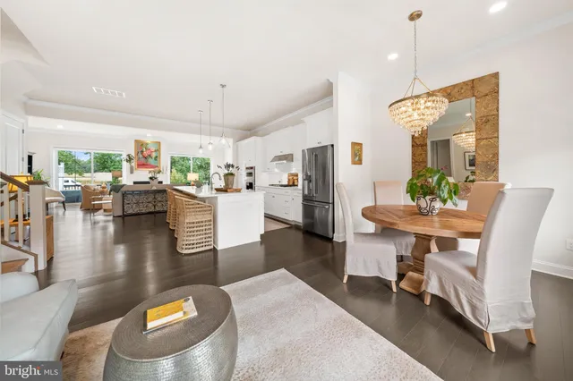 a kitchen with stainless steel appliances kitchen island granite countertop a refrigerator a stove and white cabinets with wooden floor