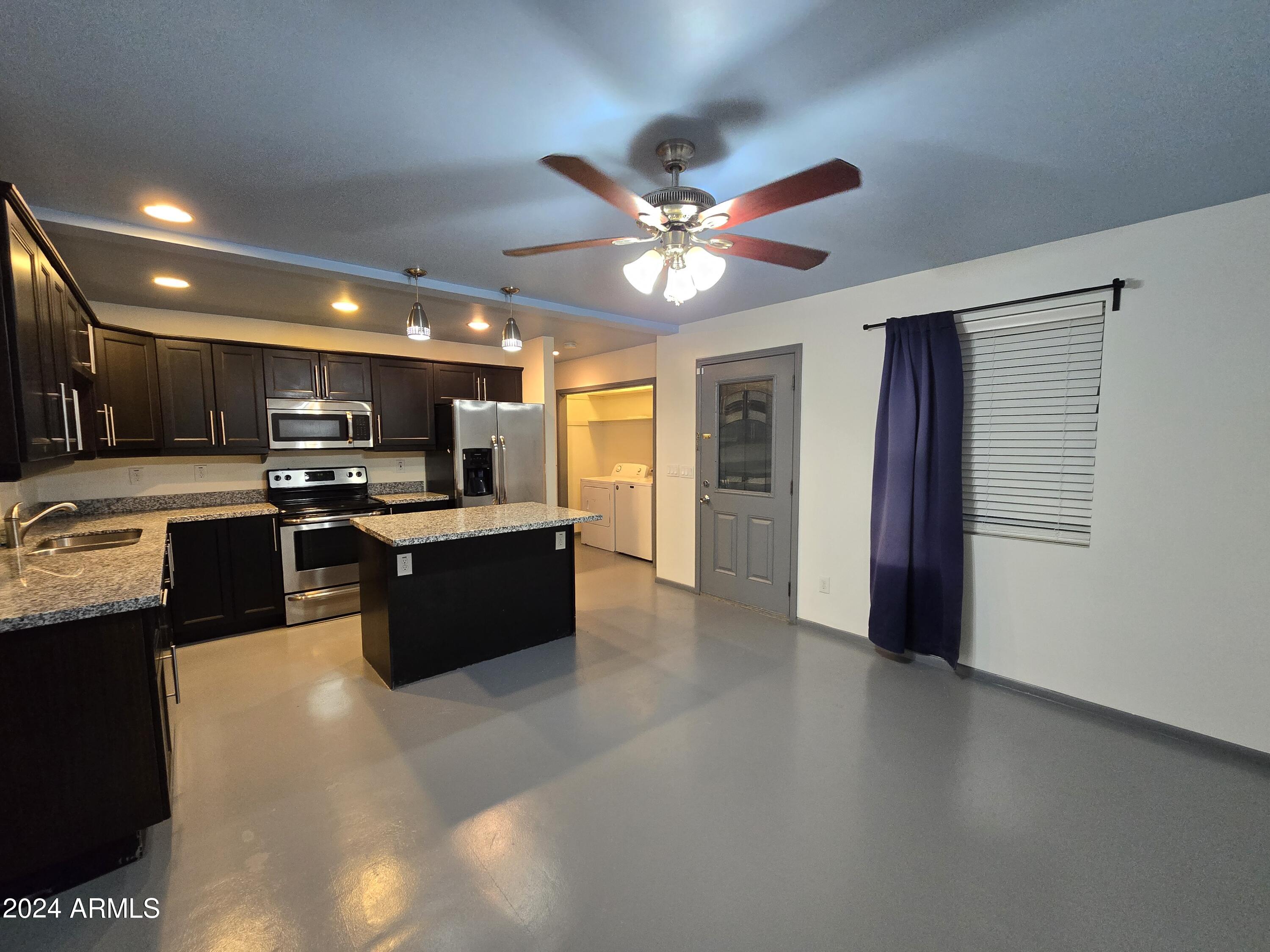2302 North 36th Street, Unit 2 Phoenix, AZ 85008 - Photo 3 of 11 a large kitchen with stainless steel appliances granite countertop a refrigerator a sink dishwasher a stove and a dining table with wooden floor
