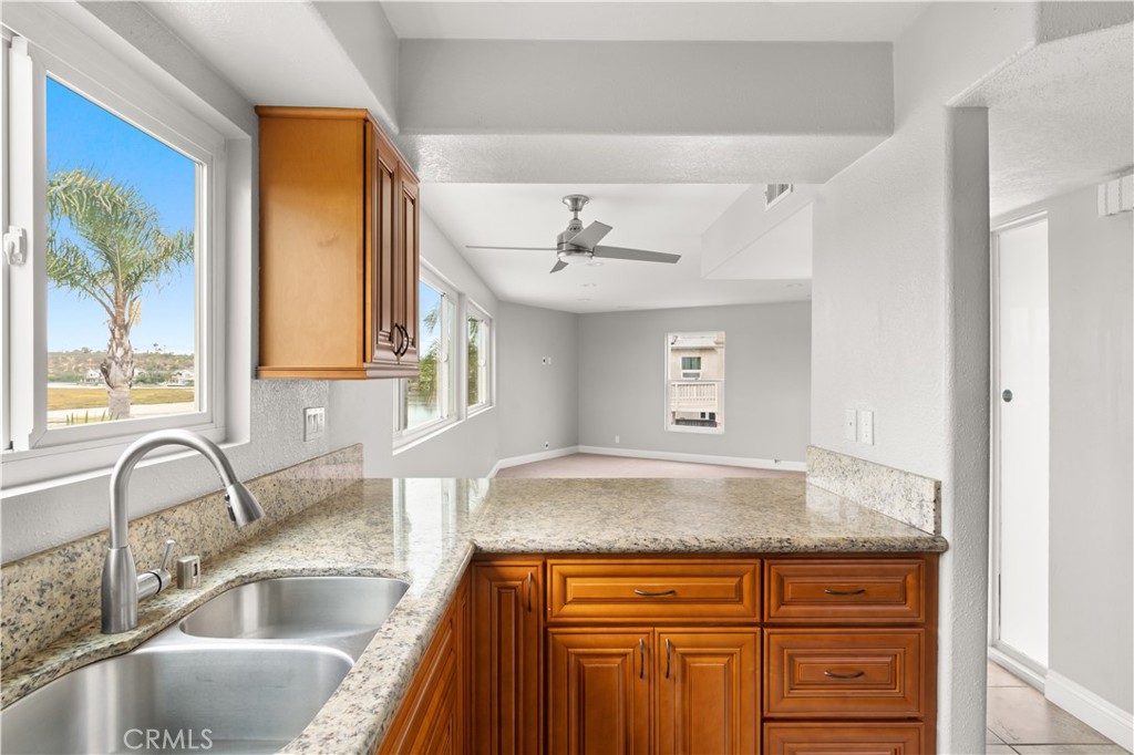 a view with granite countertop a sink and dishwasher with wooden floor