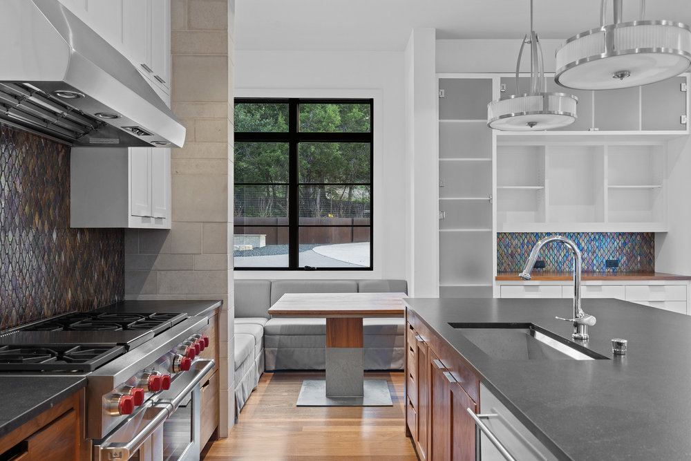 1905 Paisano Road Austin, TX 78746 - Photo 13 of 40 A well-appointed kitchen features a large range, modern cabinetry, and a bright dining nook.