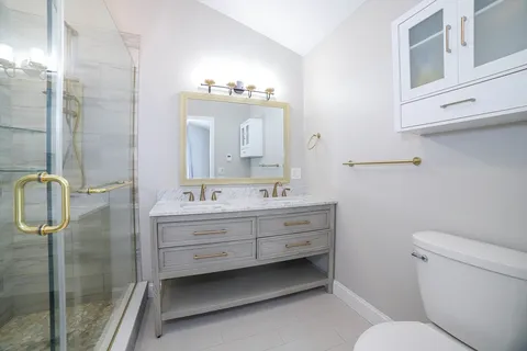 a bathroom with a double vanity sink toilet and shower