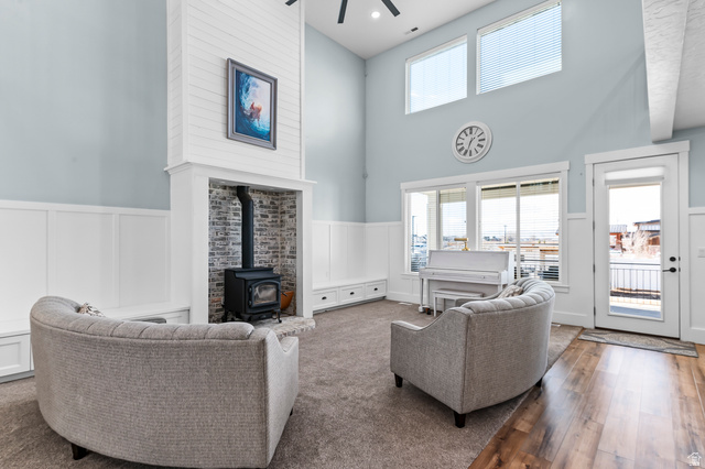 1426 South 1450th Street West Mapleton, UT 84664 - Photo 5 of 50 Vaulted ceiling living space with a shiplap fireplace surround featuring a wood-burning stove, built-in bench seating, wood-finish flooring, and large windows