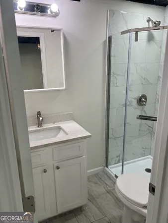 a bathroom with a granite countertop sink toilet and shower