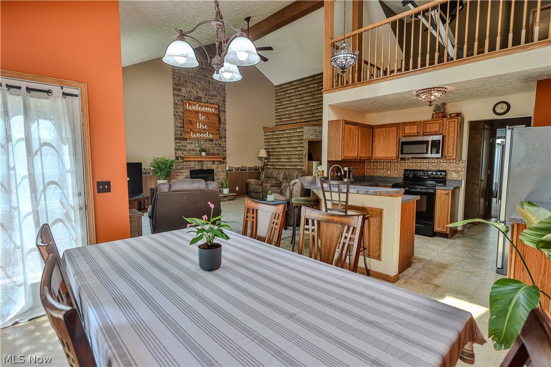 11154 Johnsford Road Southwest Beach City, OH 44608 - Photo 25 of 50 Dining area with overhead chandelier, open to a kitchen featuring wood cabinetry and an eat-at bar