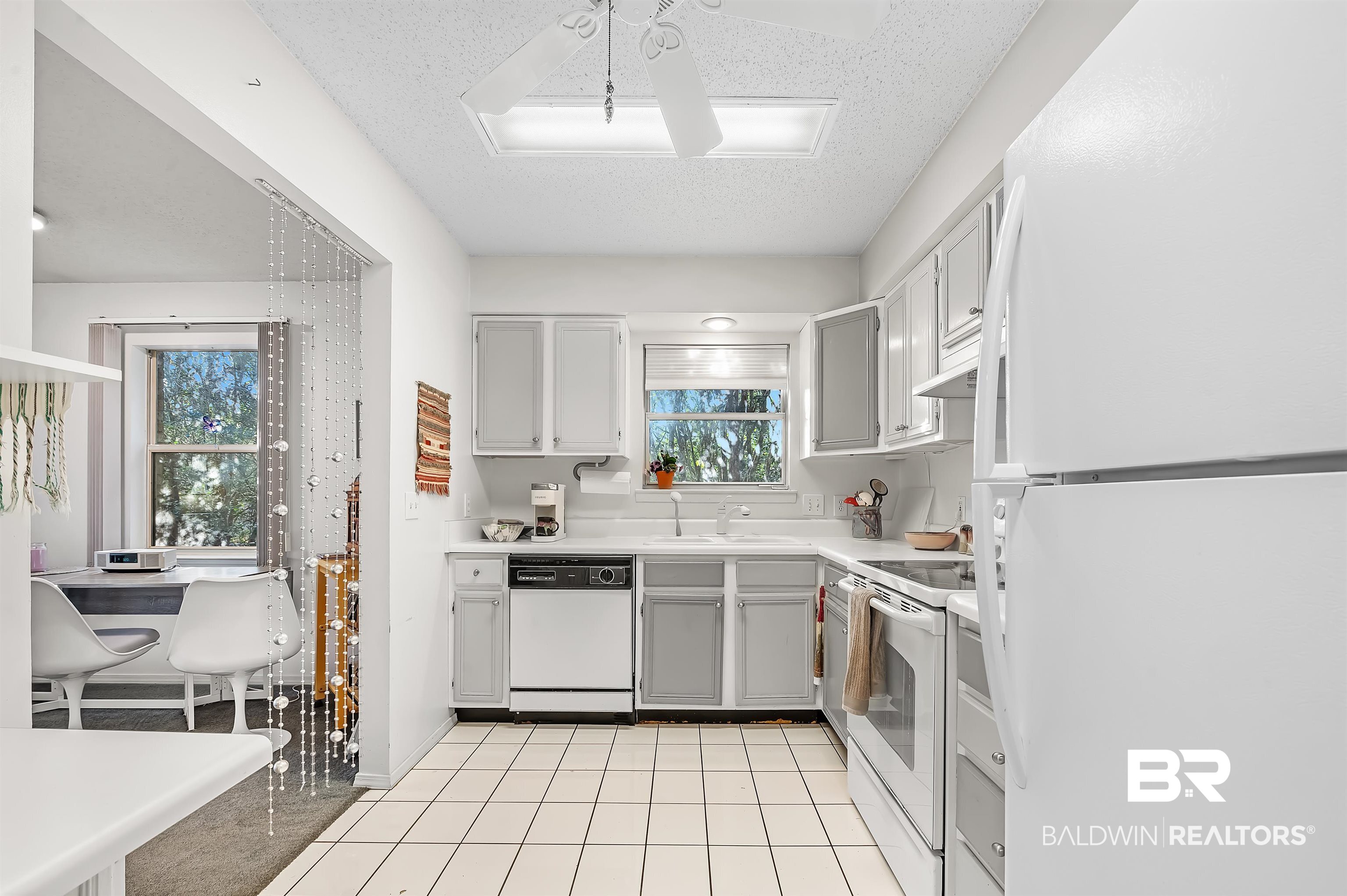 526 Ariel Avenue Foley, AL 36535 - Photo 16 of 33 Kitchen with sink, gray cabinetry, a textured ceiling, light tile patterned floors, and white appliances