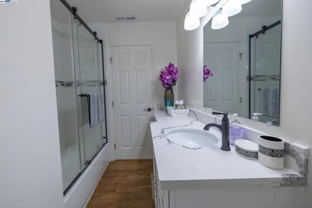 a bathroom with a granite countertop sink a large mirror and shower