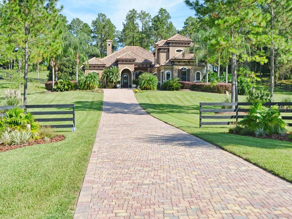 Lighted paver driveway leads you up to this magnificent equestrian home