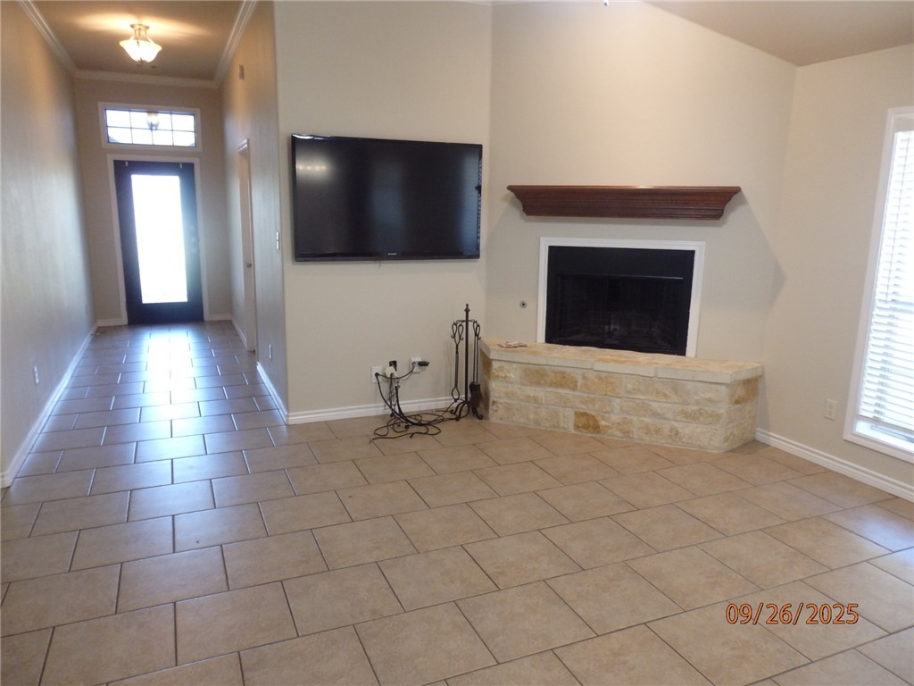 3717 Dove Crossing Lane College Station, TX 77845 - Photo 4 of 27 Unfurnished living room featuring tile patterned floors, crown molding, and a fireplace with raised hearth