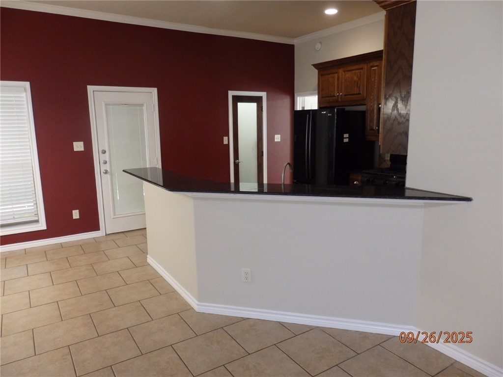 3717 Dove Crossing Lane College Station, TX 77845 - Photo 6 of 27 Kitchen with ornamental molding, a peninsula, black appliances, light tile patterned floors, and recessed lighting