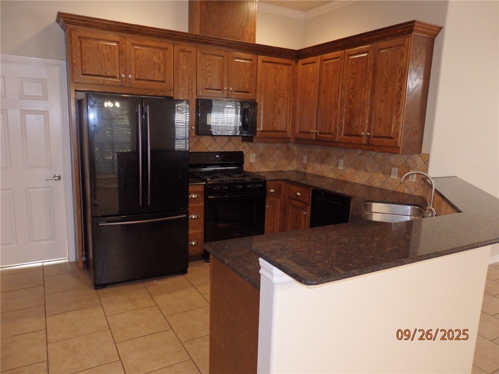3717 Dove Crossing Lane College Station, TX 77845 - Photo 7 of 27 Kitchen with decorative backsplash, black appliances, light tile patterned floors, dark stone countertops, and ornamental molding