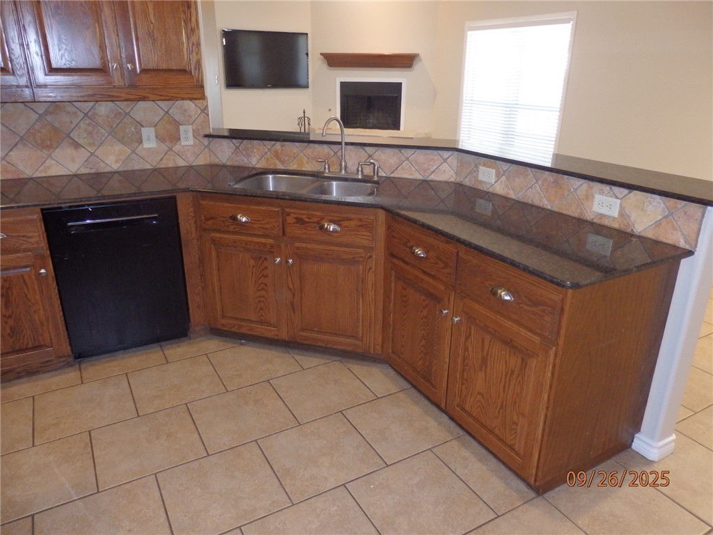 3717 Dove Crossing Lane College Station, TX 77845 - Photo 8 of 27 Kitchen featuring black dishwasher, decorative backsplash, dark stone counters, light tile patterned flooring, and brown cabinetry