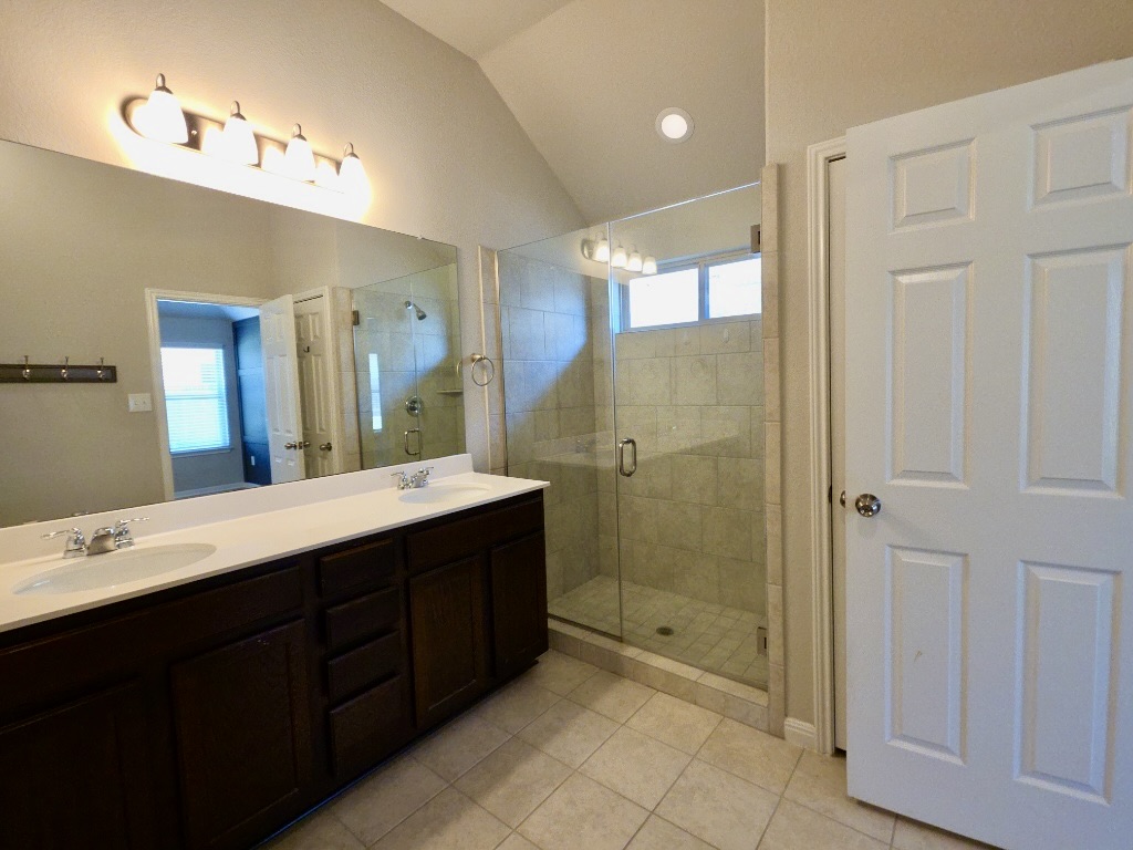 13208 Mariscan Street Manchaca, TX 78652 - Photo 11 of 31 Bathroom with double vanity, lofted ceiling, a stall shower, light tile patterned flooring, and recessed lighting