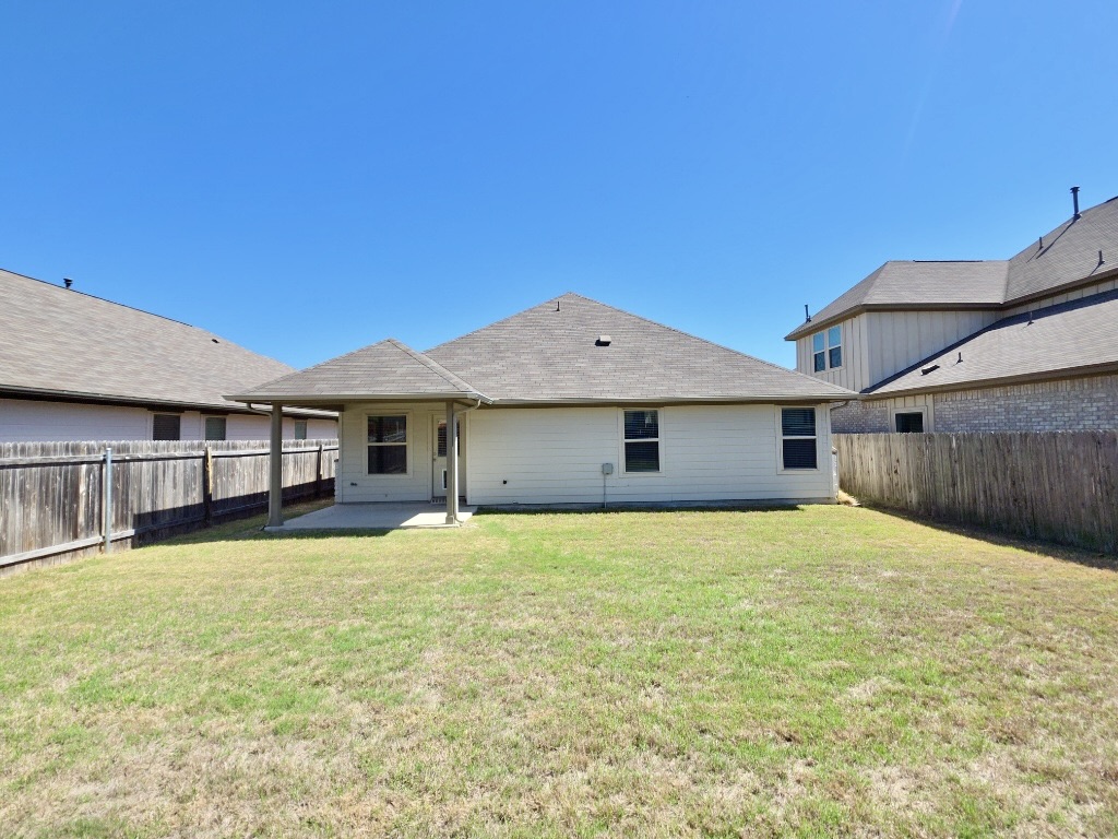 13208 Mariscan Street Manchaca, TX 78652 - Photo 20 of 31 Back of house with a patio, a fenced backyard, and a shingled roof