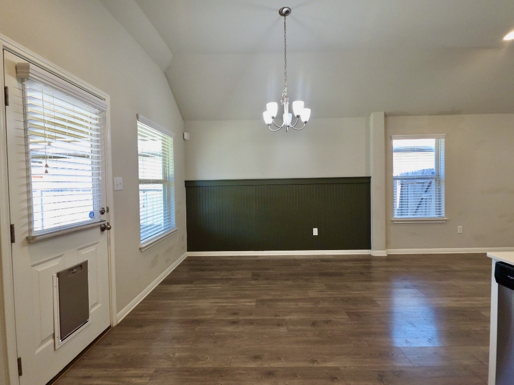 13208 Mariscan Street Manchaca, TX 78652 - Photo 8 of 31 Dining area with lofted ceiling, a chandelier, dark wood-style flooring, and a wainscoted wall