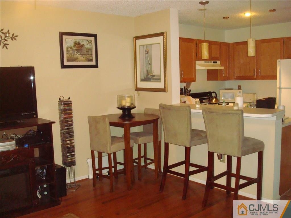 317 Edpas Road, Unit 317 New Brunswick, NJ 08901 - Photo 2 of 9 a kitchen with stainless steel appliances granite countertop a dining table chairs and a refrigerator a stove top oven with wooden floor