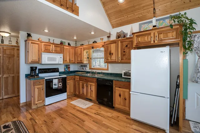 a kitchen with stainless steel appliances granite countertop a stove a sink dishwasher and cabinets with wooden floor