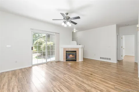 a view of an empty room with wooden floor fireplace and a window