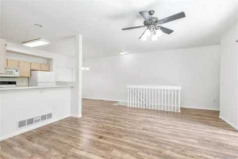 a view of a kitchen with wooden floor and a ceiling fan