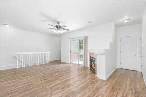a view of an empty room with a window and a kitchen