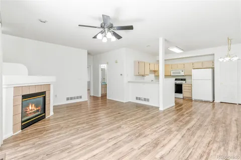a view of a livingroom with a fireplace a ceiling fan and wooden floor