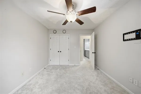 an empty room with chandelier fan and windows