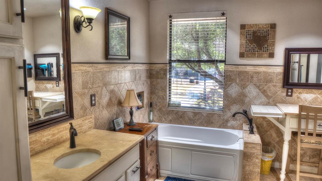 187 Roy Chisum Road Leakey, TX 78873 - Photo 26 of 40 a bathroom with a granite countertop sink a toilet a mirror and window
