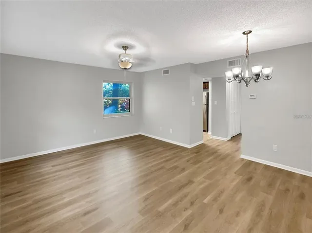 a view of empty room with wooden floor and ceiling fan