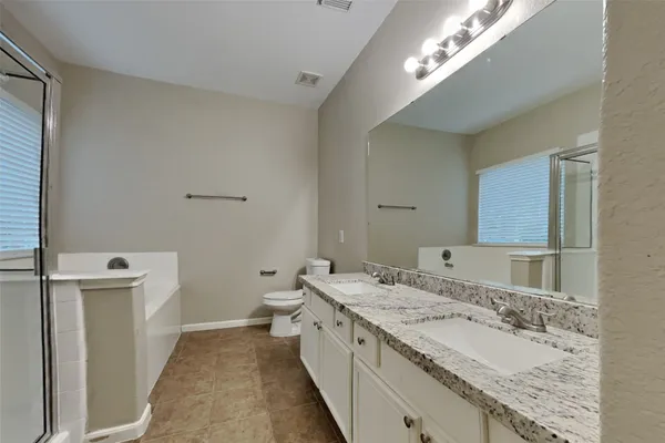 a spacious bathroom with a granite countertop double vanity sink and a mirror