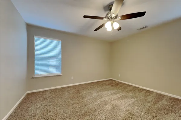 an empty room with windows and fan