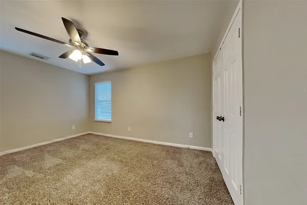 a view of an empty room and chandelier fan