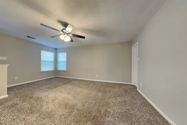 an empty room with windows and ceiling fan