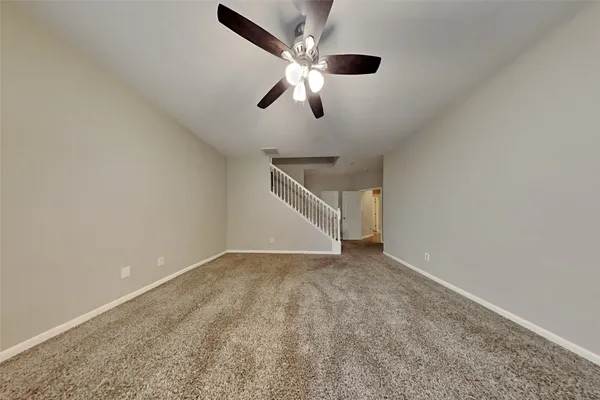 an empty room with ceiling fan and window