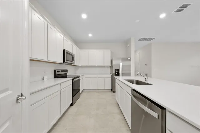 a kitchen with white cabinets appliances and sink