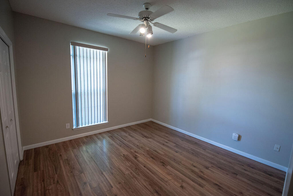 4565 Parkwood Court Niceville, FL 32578 - Photo 36 of 48 an empty room with wooden floor chandelier fan and windows