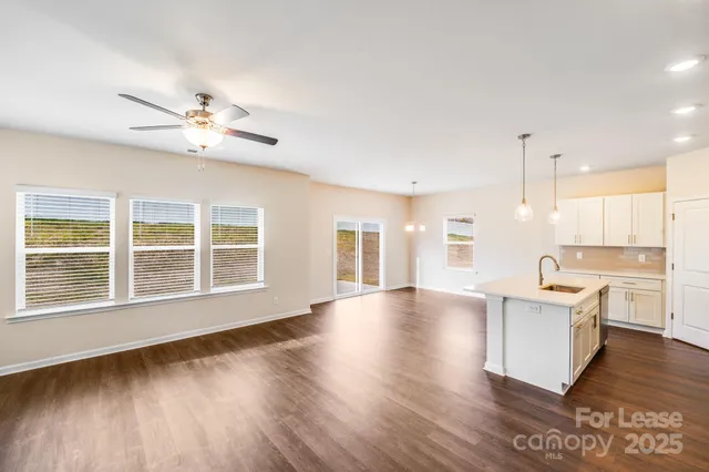 a view of an empty room with a kitchen and wooden floor