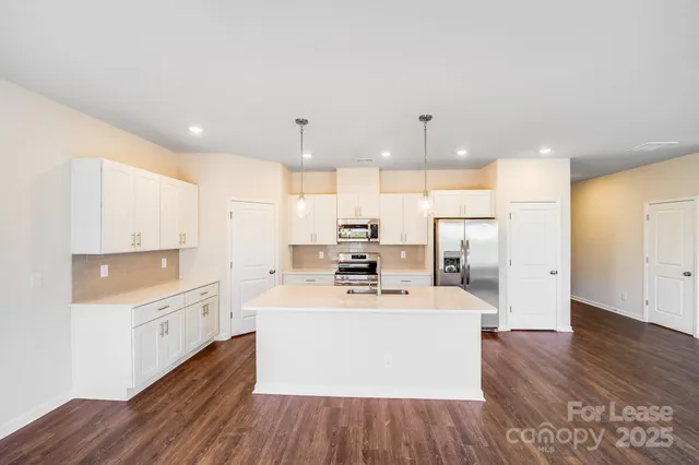 a large white kitchen with wooden floor and stainless steel appliances