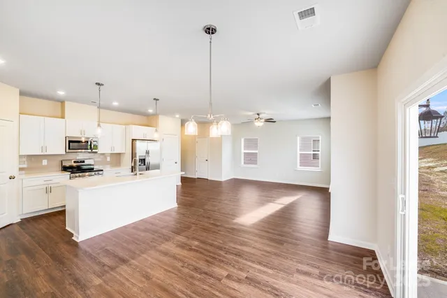 a view of a kitchen with kitchen island a sink wooden floor and a fireplace