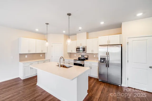 a kitchen with a refrigerator a sink and wooden floor