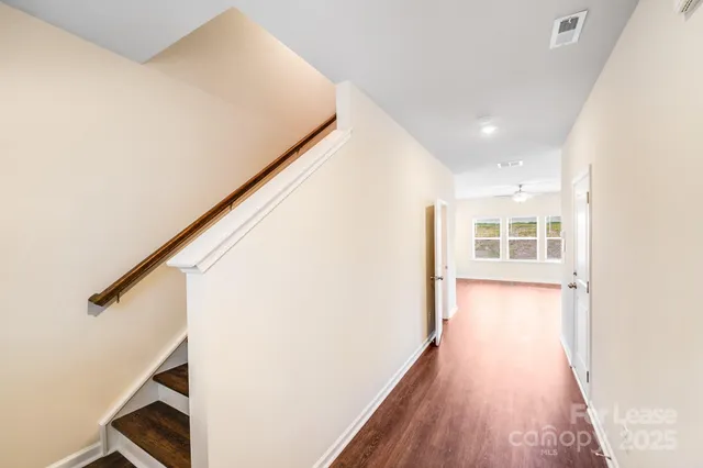 a view of a hallway with wooden floor and staircase