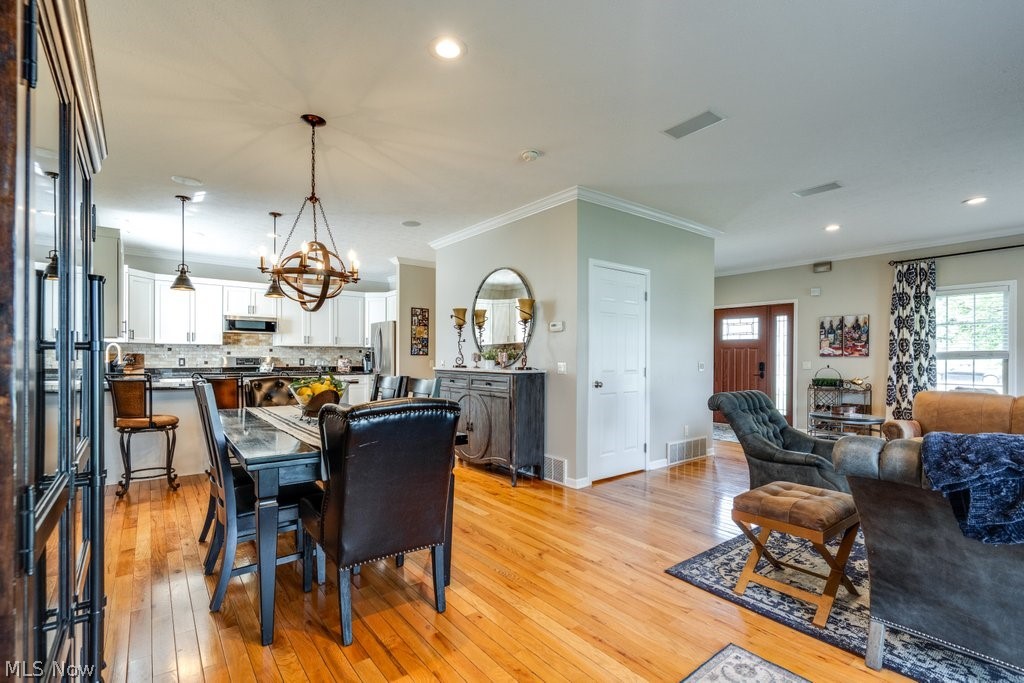 6325 Brecksville Road Independence, OH 44131 - Photo 12 of 50 Open-concept living area featuring hardwood floors, a kitchen with white cabinetry and a tiled backsplash, and a dining area with a chandelier