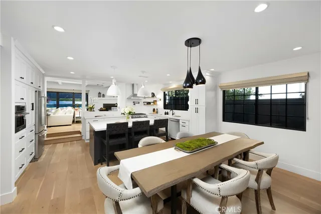 a large kitchen with stainless steel appliances a stove a sink dishwasher and a refrigerator with wooden floor