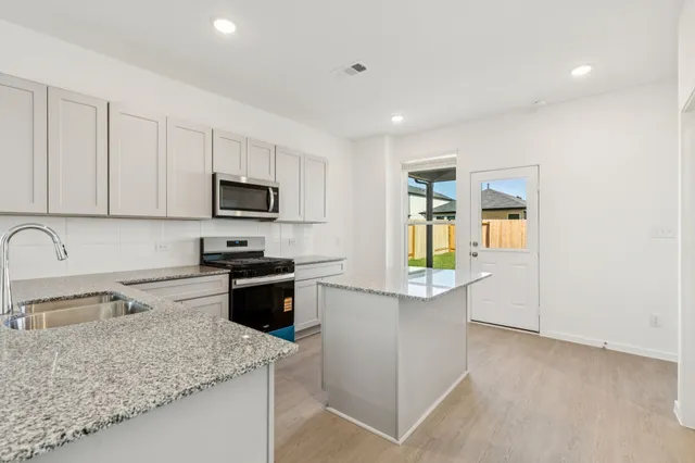 a kitchen with a sink a stove top oven and white cabinets