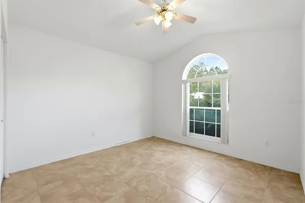 an empty room with chandelier fan and wooden floor
