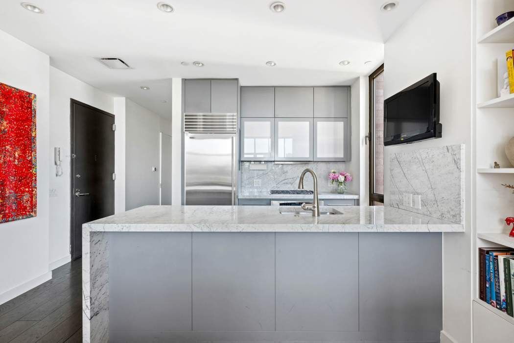210 Lafayette Street, Unit 7A Manhattan, NY 10012 - Photo 5 of 13 a kitchen with stainless steel appliances granite countertop a sink a microwave a refrigerator and white cabinets with wooden floor