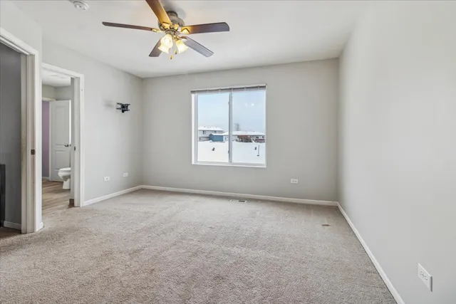 an empty room with windows and fan