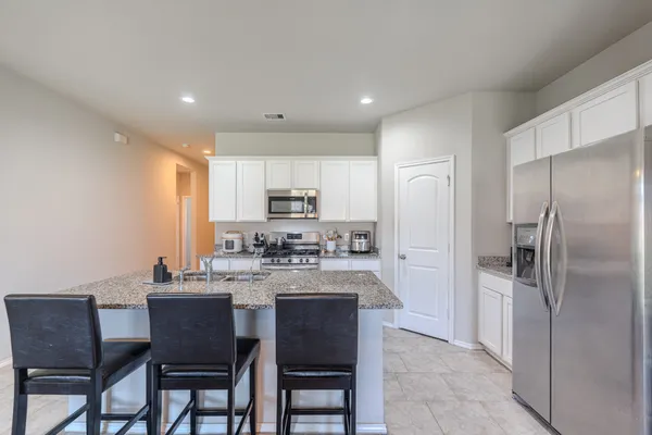 a kitchen with refrigerator a sink and chairs